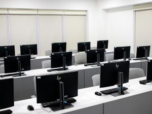 Spacious and minimalist computer lab with rows of black monitors and sleek furniture.