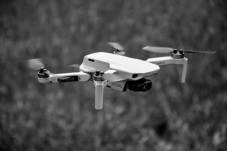 A grayscale image of a hovering drone outdoors, showcasing its sleek design and motion.